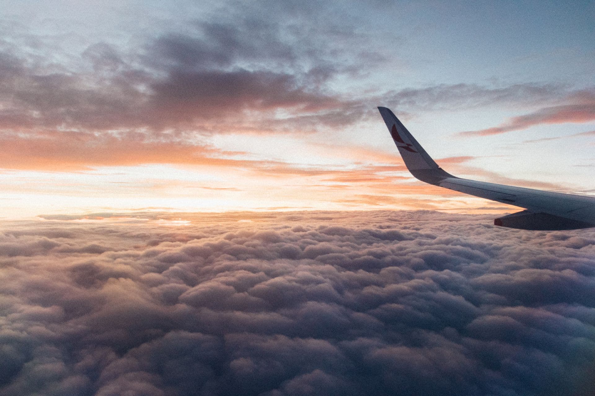 Airplane wing above sunset clouds